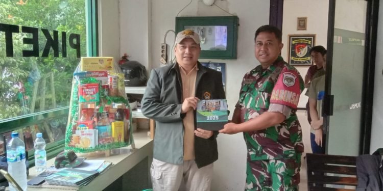 Ketua PC LDII Cimanggis Hady Dwi Purbaya menyerahkan kalender LDII tahun 2025 kepada petugas piket Koramil 06 Cimanggis. (LINES)